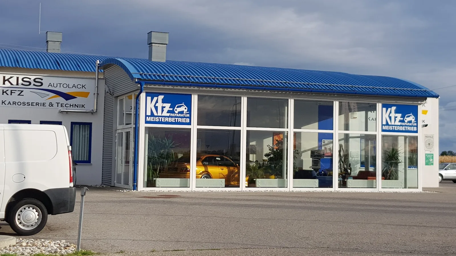 Fassade von Kiss Autolack mit Firmenzeichen und KFZ-Meisterbetrieb-Schildern